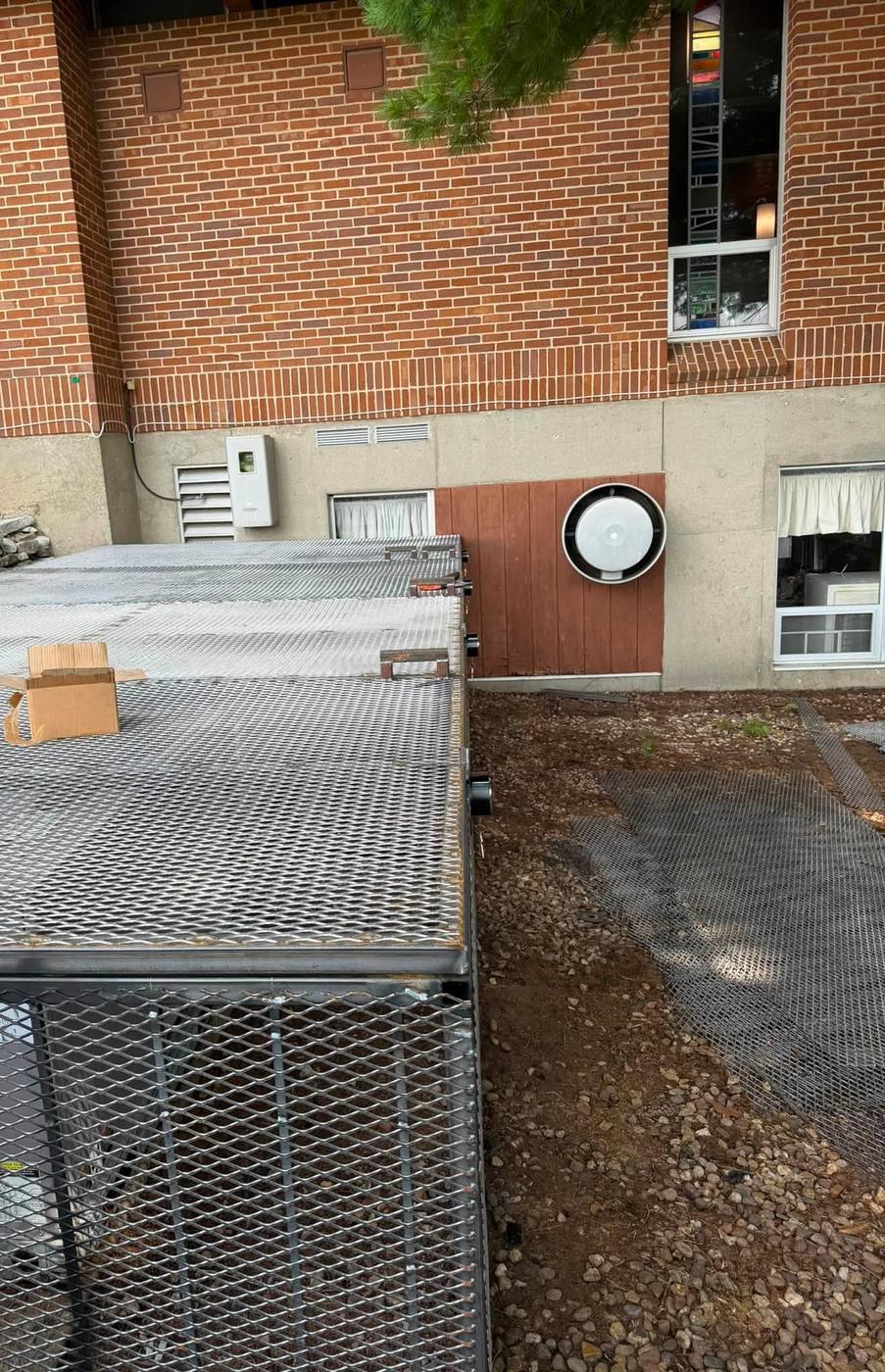 A finished expanded metal cage built around ground mounted air conditioning units
