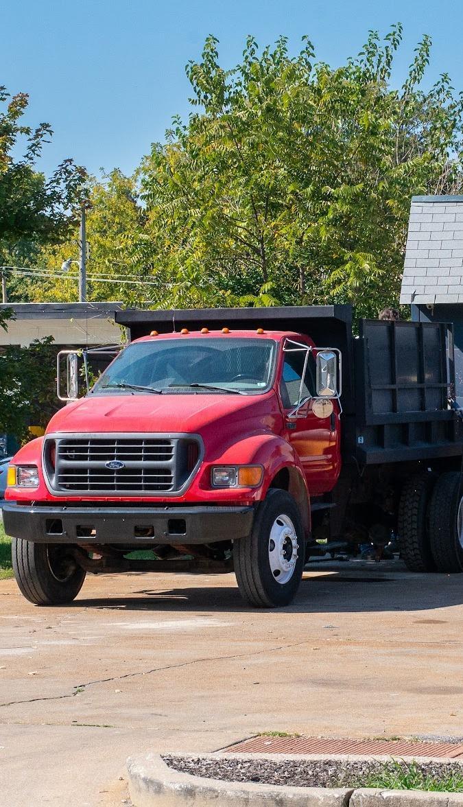A red flatbed dump truck parked at the open workshop bay