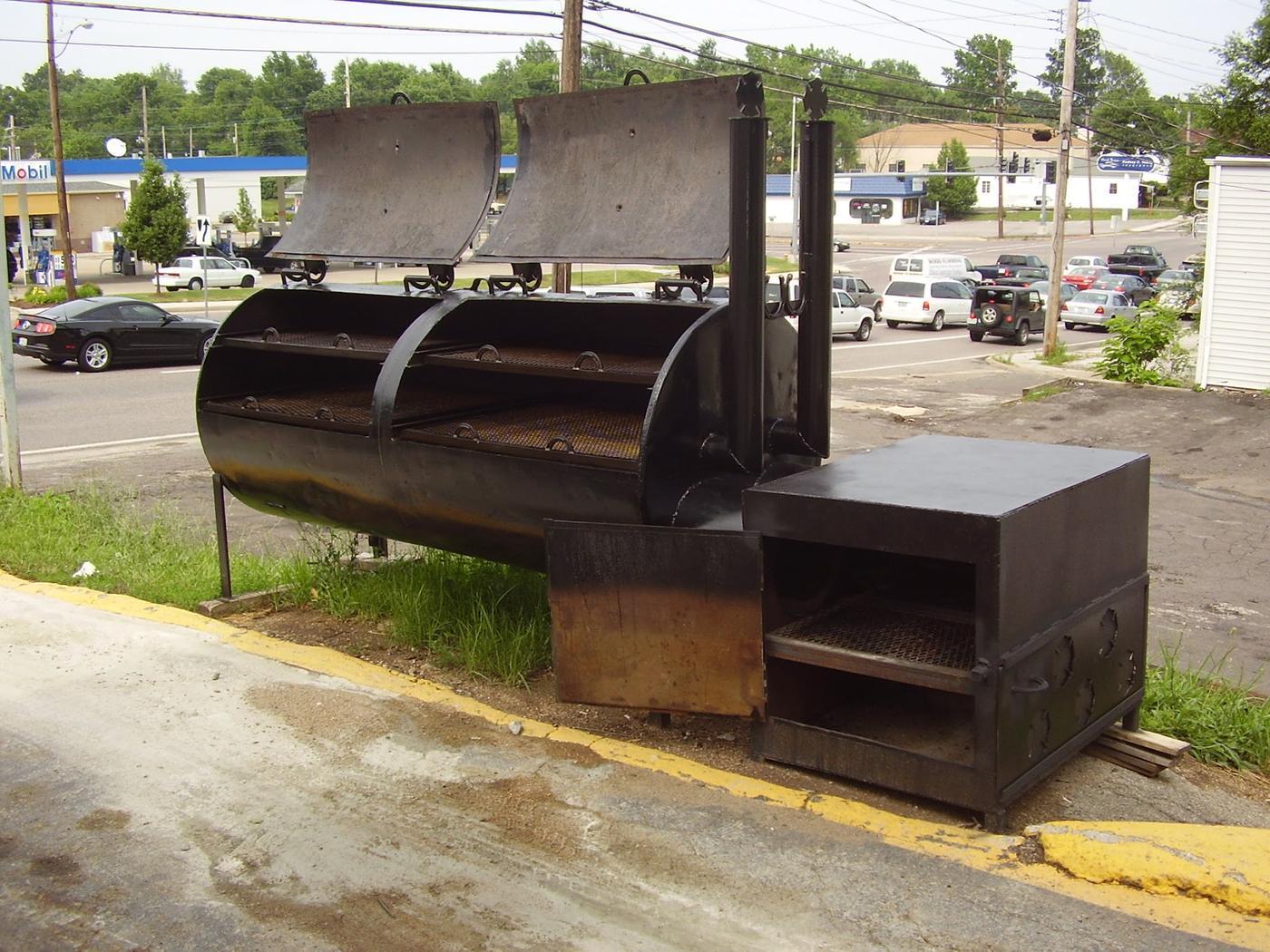 A large custom built barbecue smoker with twin hinged lids, chimney stacks, a firebox and a warming box